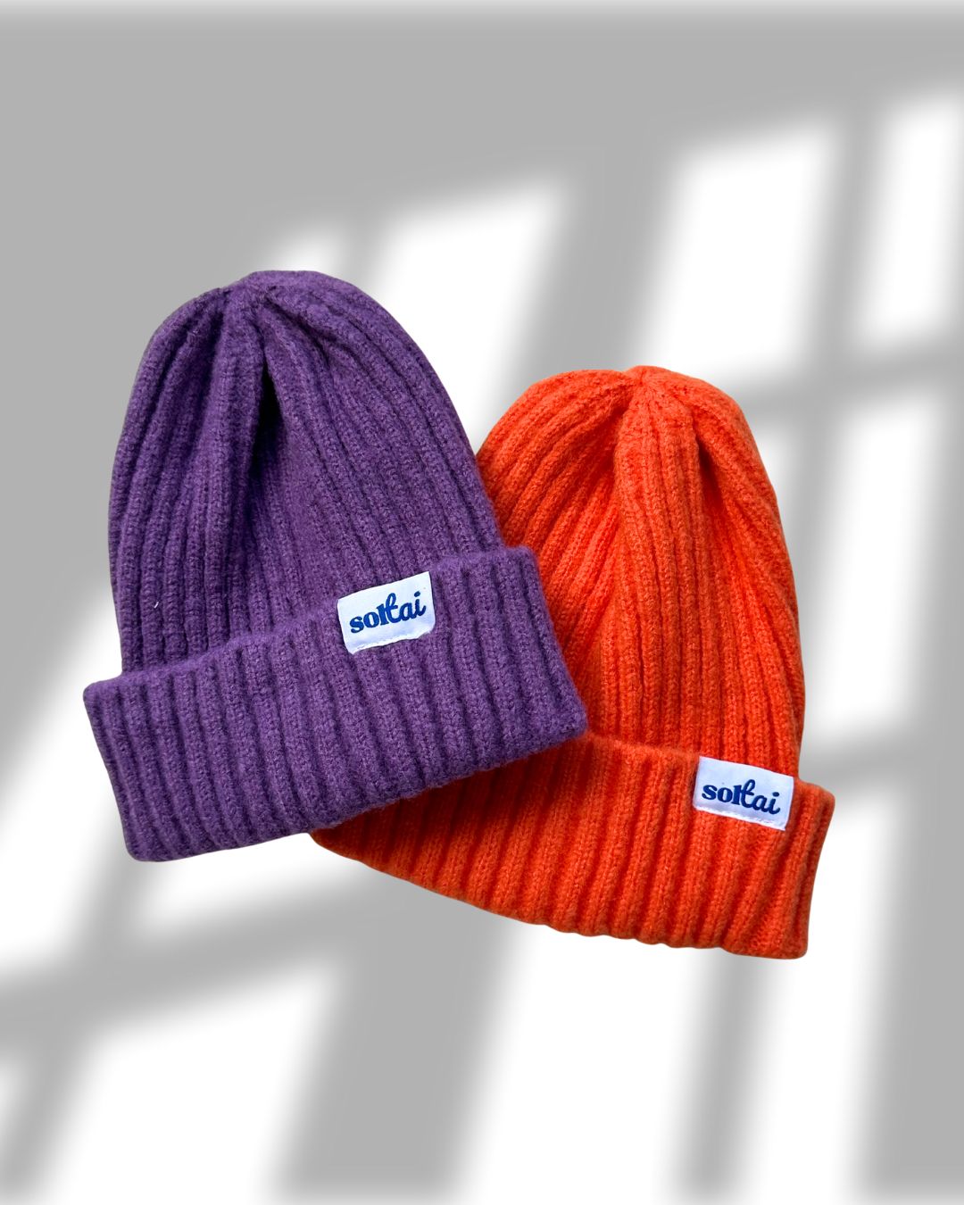 Purple and orange toddler beanie baby hats with Soltai logo on a white background