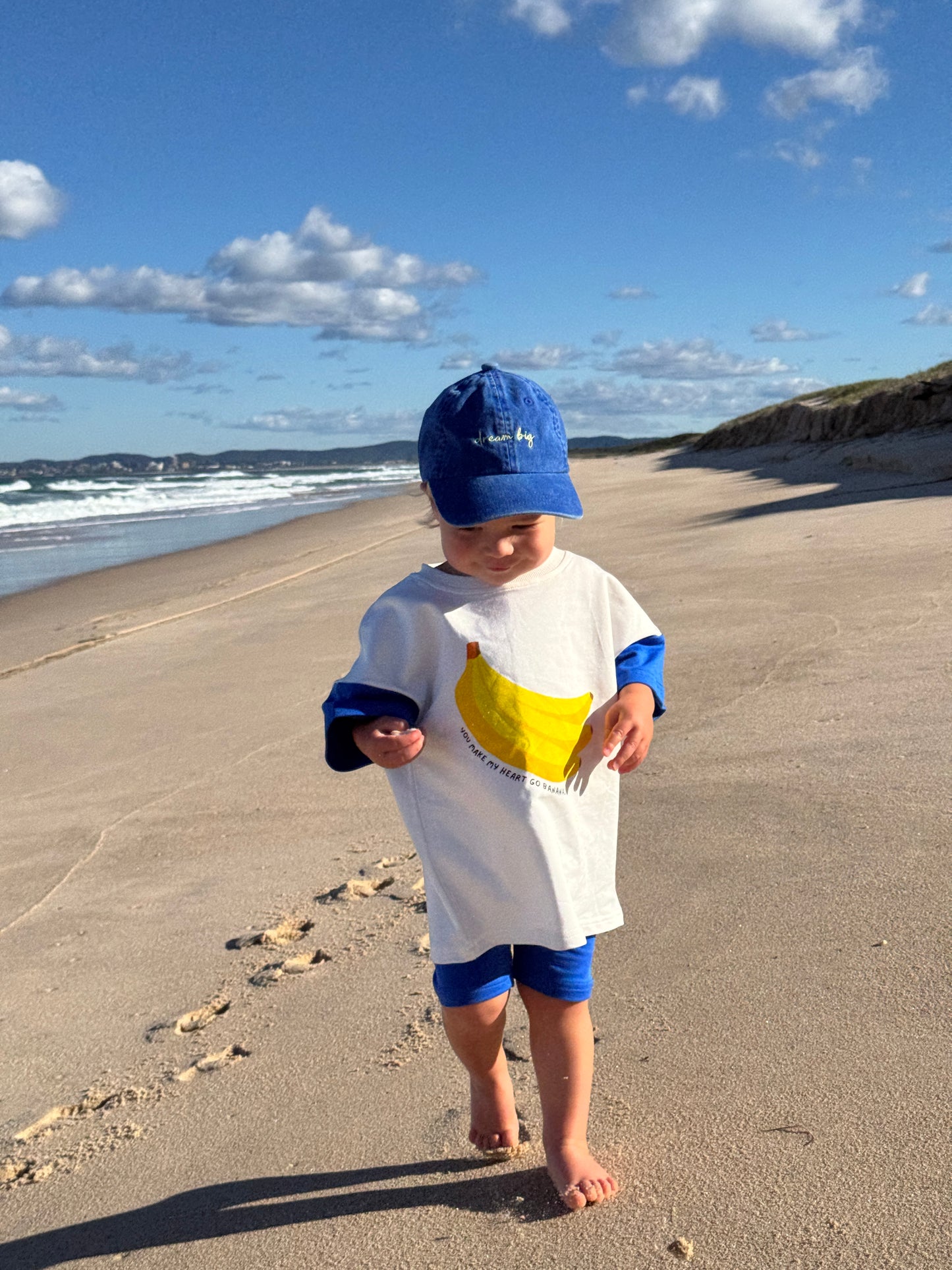 Toddler wearing banana print cotton outfit, playful Aussie kidswear, bright blue and white matching outfit with bike shorts for toddlers and babies