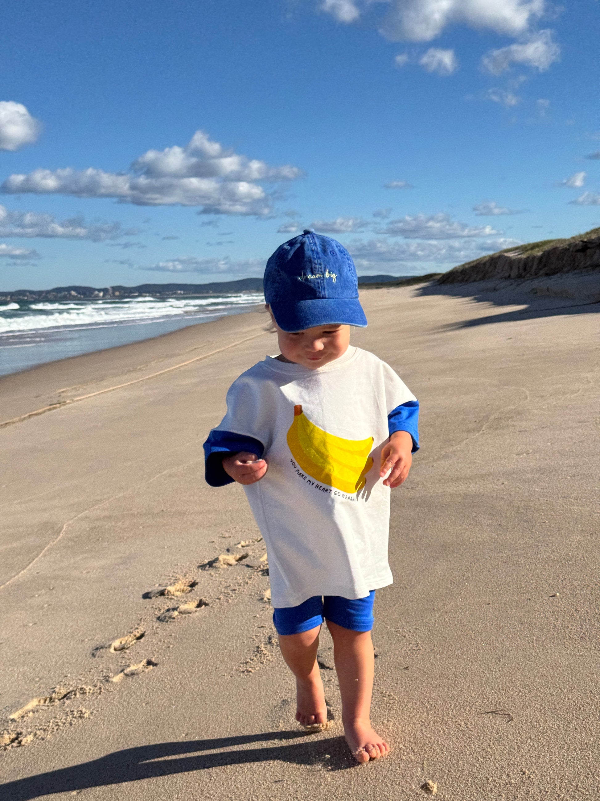 Toddler wearing banana print cotton outfit, playful Aussie kidswear, bright blue and white matching outfit with bike shorts for toddlers and babies