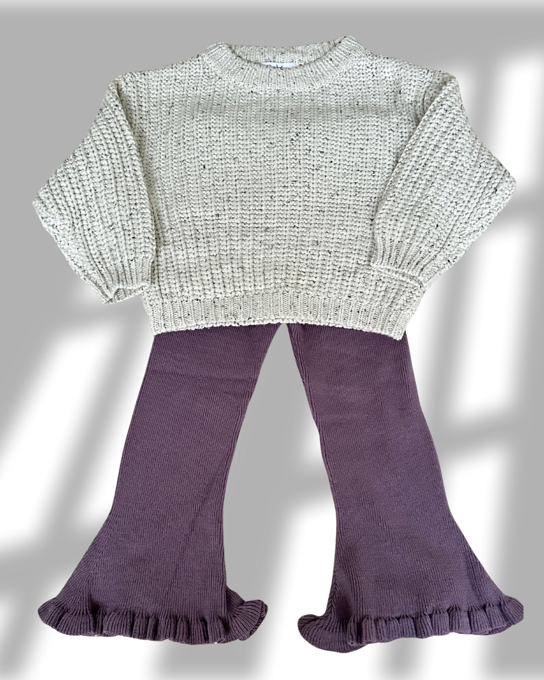 Knitted sweater and purple leggings on a gray background