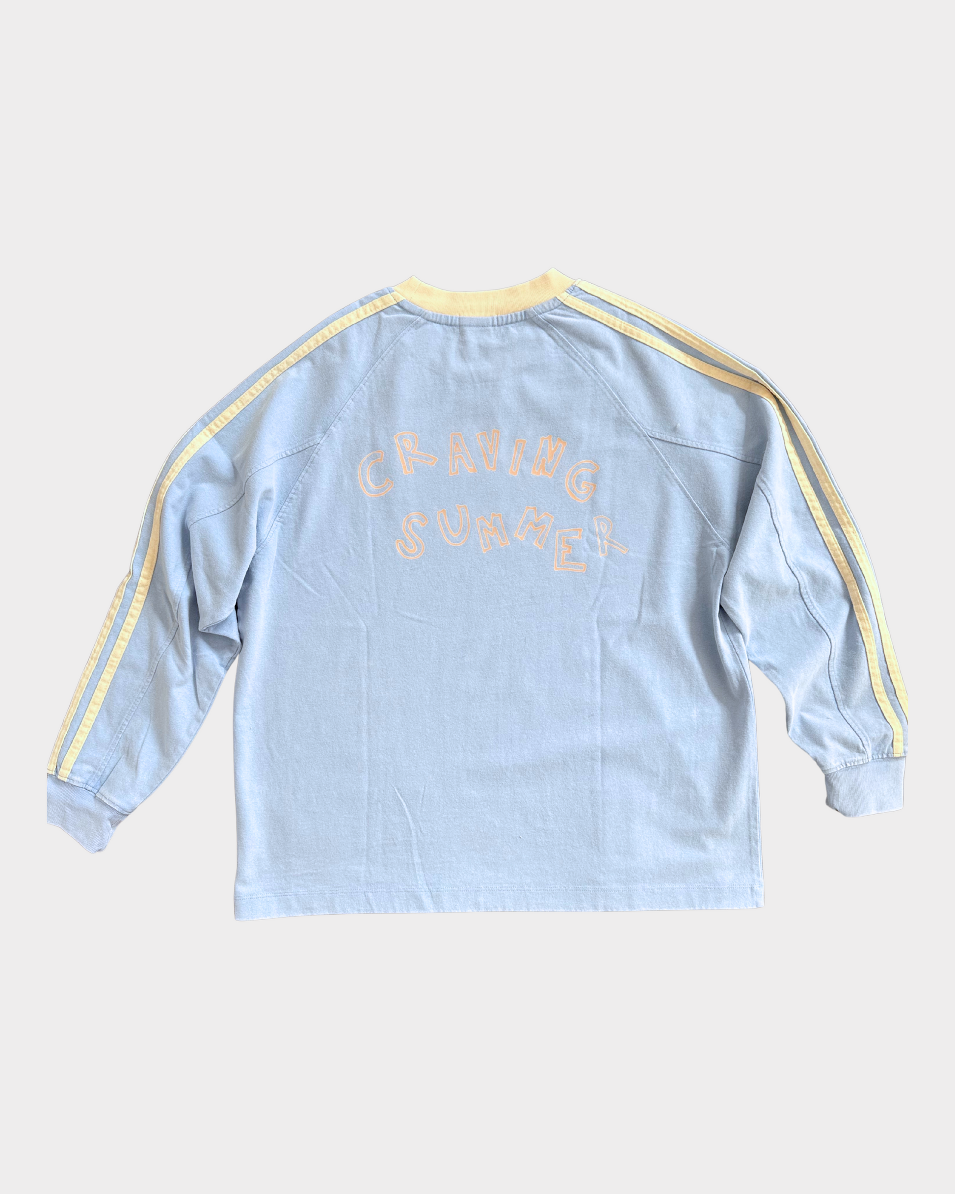 Light blue long-sleeve shirt with yellow accents on a white background